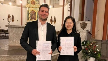 David Kiefer und Eunsu Kim mit Urkunden in der Hand in einer Kirche