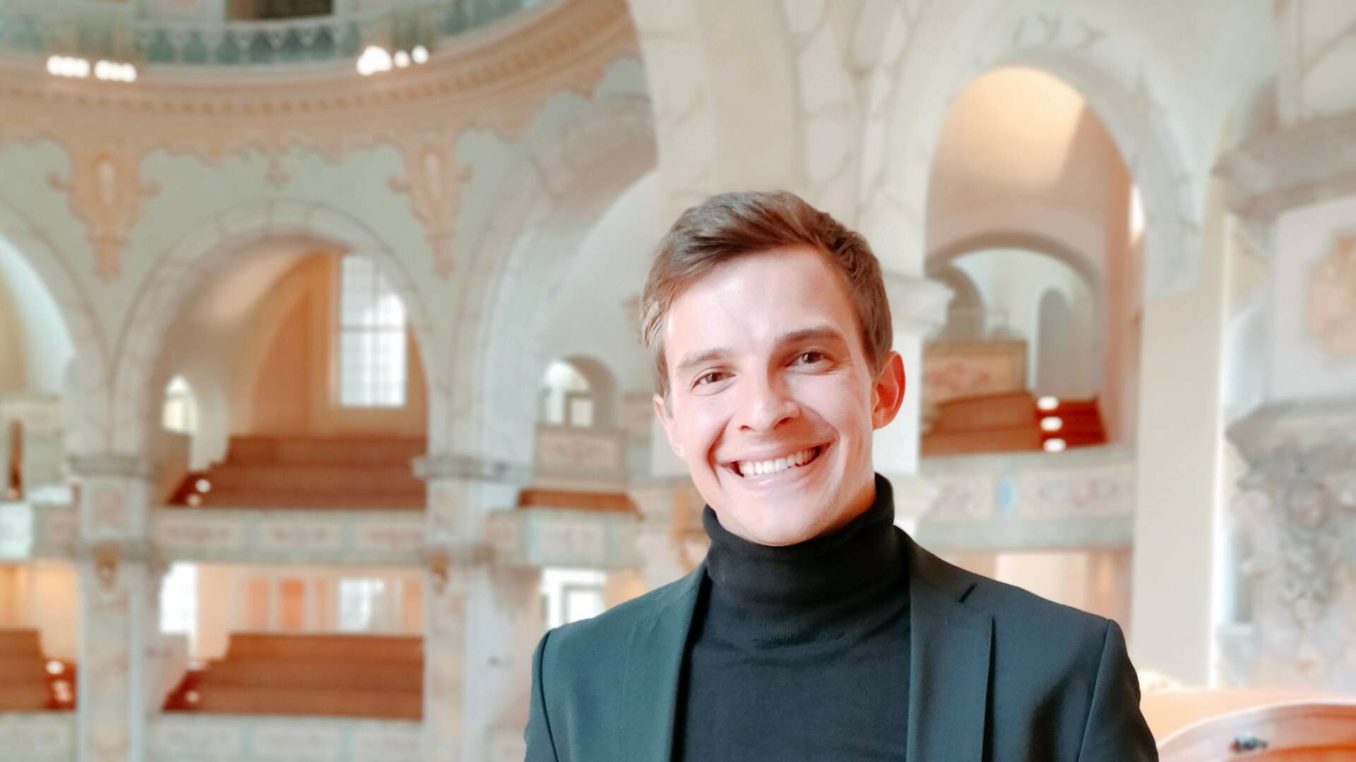 Niklas Jahn steht in einem schwarzen Jackett in der Dresdner Frauenkirche