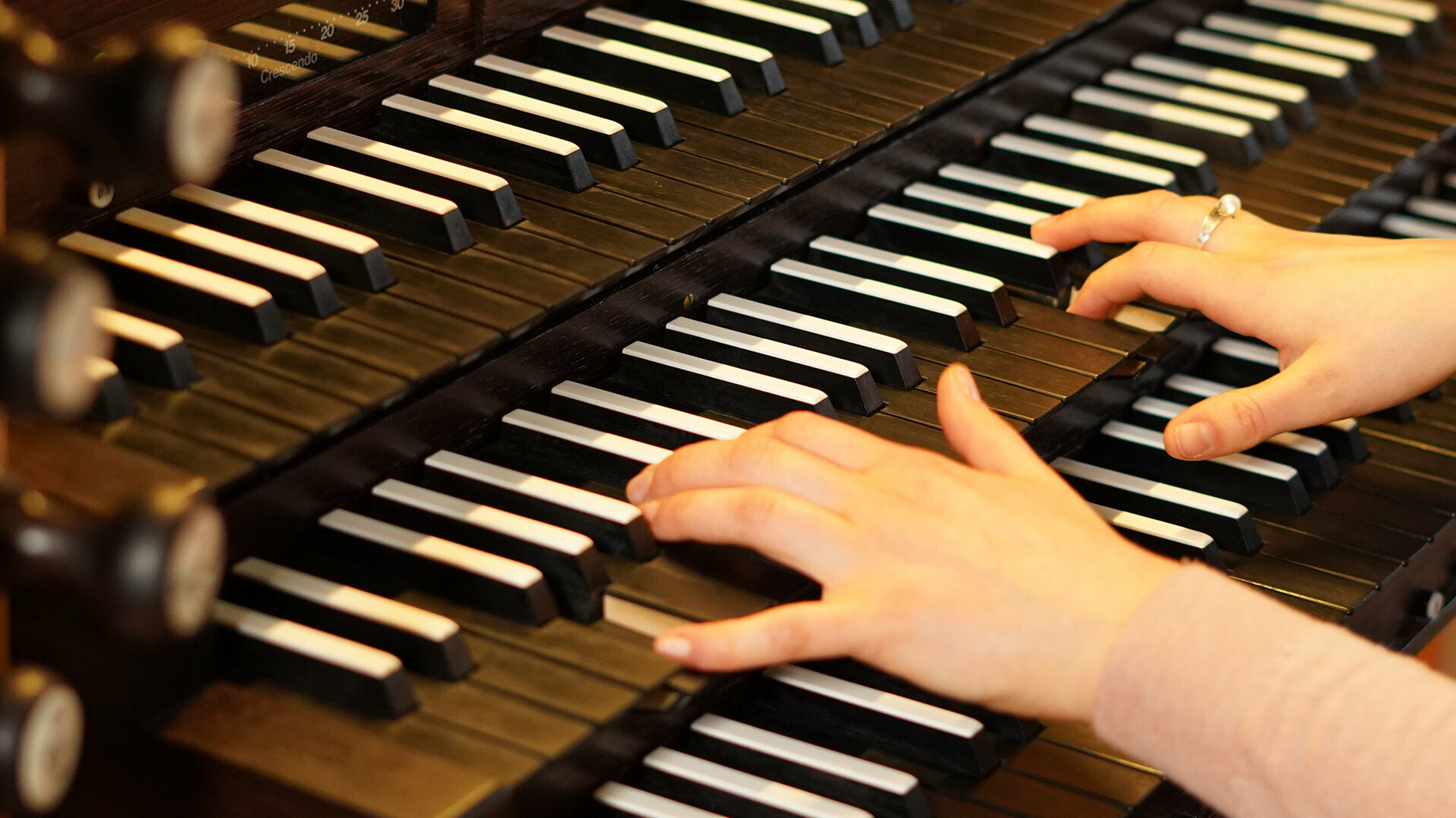 Zwei Hände spielen auf einer dreimanualigen Orgel
